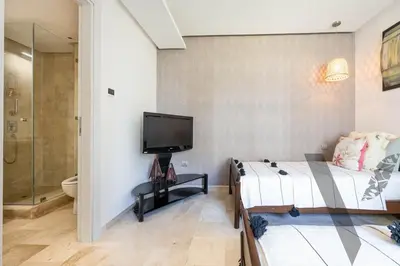 a bedroom with a bed and a tv on a wall at Seaside Luxury 3BR With Pool & Private Beach Access in Bouznika
