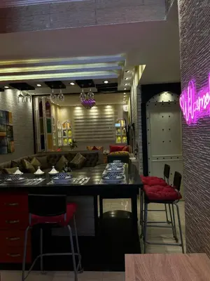 a restaurant with a bar with red chairs and a counter at Grand appartement romandie in Casablanca