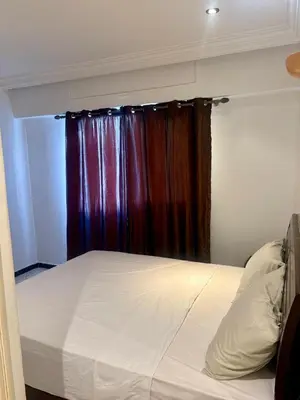 a bed in a room with a window with a curtain at Appartement en plein cœur de Agdal in Rabat