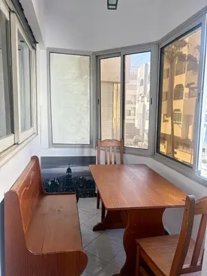 a dining room with a table and chairs and windows at Appartement en plein cœur de Agdal in Rabat