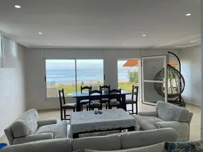 a living room with a table and chairs and the ocean at Maison Bord de Mer Skhirate in Skhirat