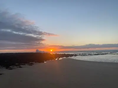 a sunset on a beach with the sun setting at Maison Bord de Mer Skhirate in Skhirat