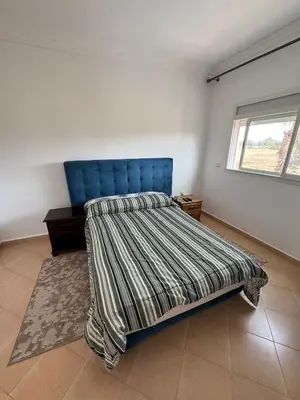 a bedroom with a bed with a blue headboard and a window at Villa moderne en bord de mer in Skhirat