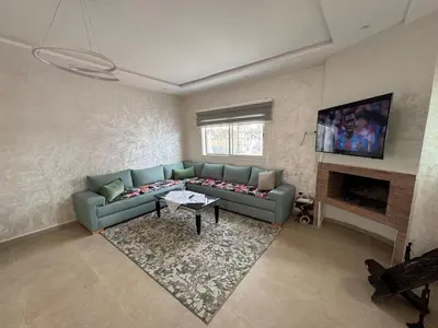 a living room with a blue couch and a tv at Villa moderne en bord de mer in Skhirat