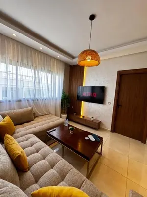 a living room with a couch and a tv at Cozy & Chill à 30min terrain de foot Netflix, AC pool & beach 2 min, in Bouznika
