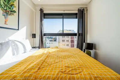 a yellow bed in a bedroom with a large window at C14- 1BR Luxury Apartment -Terrace Majorelle in Casablanca