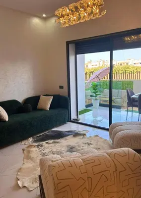 a living room with a green couch and a large window at Appartement chic a 5 mins de la plage in El Harhoura