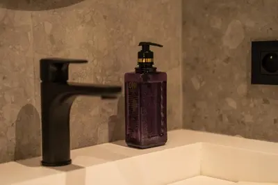 a bottle of soap sitting on a sink next to a faucet at C13 - 1BR Suite - Private Gym - Terrace - Rooftop in Maarif