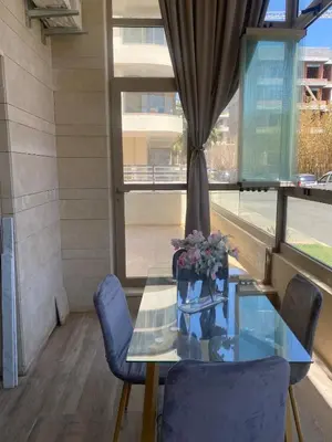 a dining room with a glass table and blue chairs at New ground floor apartment - Large terrace direct access to pool in Bouznika