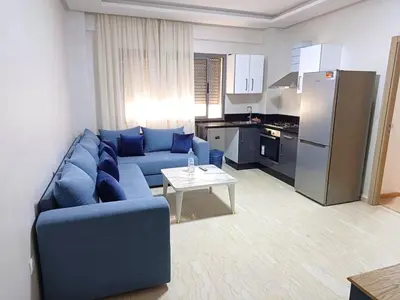 a living room with a blue couch and a kitchen at Apartment kamal park F1 in Mohammedia