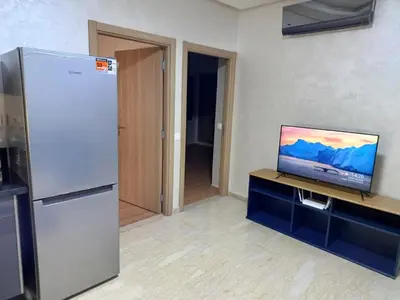 a kitchen with a refrigerator and a tv on a counter at Apartment kamal park F1 in Mohammedia