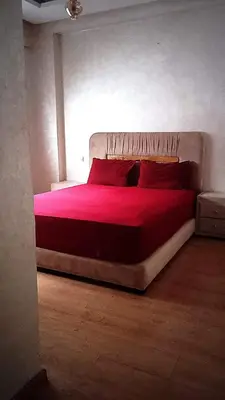 a bedroom with a large bed with red sheets and pillows at Apartment kamal park F1 in Mohammedia