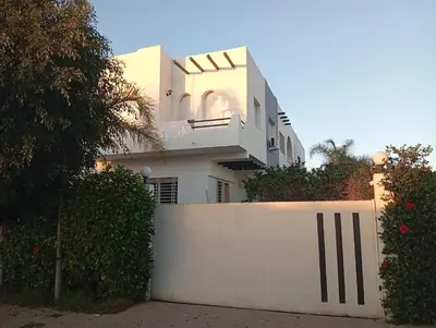 a white house behind a white fence at Beach & Art Bungalow in El Harhoura