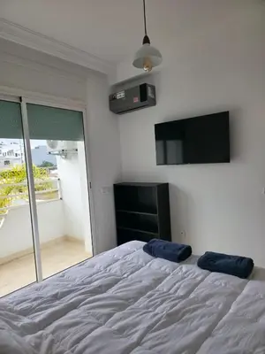 a bedroom with a bed and a flat screen tv at Beach & Art Bungalow in El Harhoura