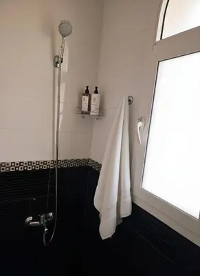 a bathroom with a shower with white towels and a window at Beach & Art Bungalow in El Harhoura