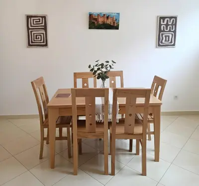 a wooden dining room table and chairs with a vase of flowers at Beach & Art Bungalow in El Harhoura