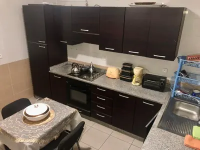 a kitchen with black cabinets and a table and a stove at Central Casablanca Apartment Steps from Hassan II Area in Casablanca
