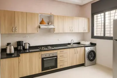 a kitchen with wooden cabinets and a washer and dryer at Spacieux RDC avec salle de sport privative in Bouznika