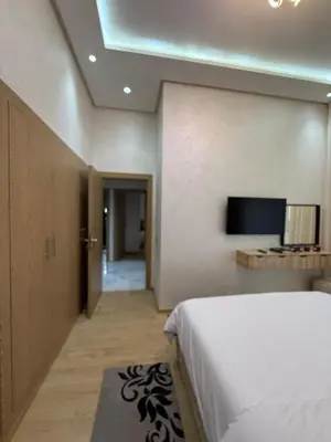 a bedroom with a bed and a flat screen tv at Appartement 3 chambres avec piscine, proche de la plage Zenâta Eco City in Aïn Harrouda