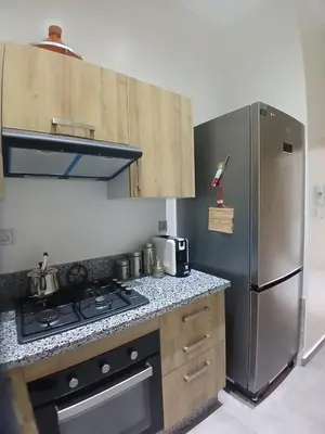 a kitchen with a stove and a stainless steel refrigerator at Appartement 3 chambres avec piscine, proche de la plage Zenâta Eco City in Aïn Harrouda