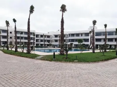 a courtyard with palm trees in front of a building at Appartement à louer Eden Mansouria Residence in Mansouria
