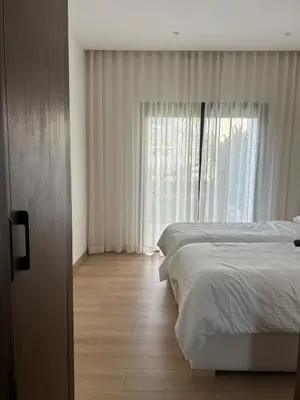 a bedroom with two beds and a large window at Appartement Steps from Anfa Park Fanzone in Casablanca