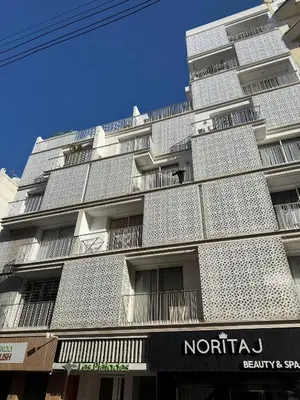 a tall white building with a sign in front of it at Maya Suites - Cozy Flat with Terrace & Garden in Casablanca