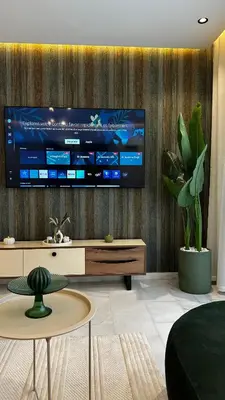a living room with a large tv on a wall at studio luxe rooftop & gym quartier des princess in Casablanca