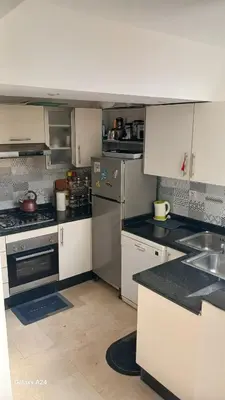 a kitchen with white cabinets and a sink and counters at Bel Appartement au cœur de Casablanca in Casablanca