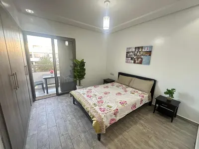 a bedroom with a bed and a table and a window at Marbella beach residency in Mansouria