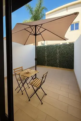 a table and chairs with an umbrella on a patio at My Cosy Place Cosy Apartment Casa gare Oasis in LʼOasis
