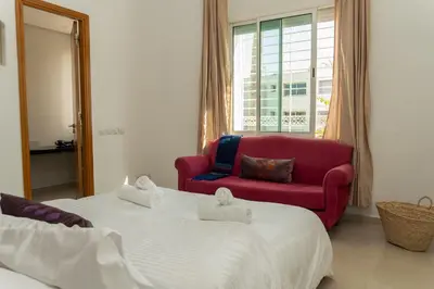 a bedroom with two beds and a red chair at Upper floor of a villa, Modern and bright in Rabat