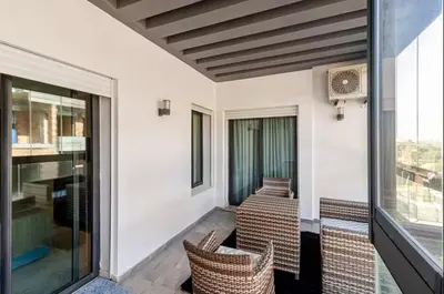 a balcony with wicker chairs and a table and windows at Large Comfort Duplex Casablanca Center in LʼOasis