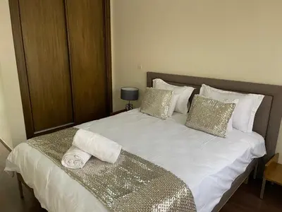 a large white bed with gold and white pillows at Magnifique Appartement familial avec piscine in Mohammedia