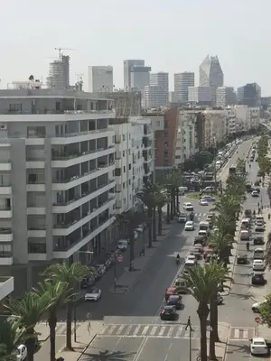 a city street with cars and palm trees and buildings at Studio luxueux CFC in Casablanca