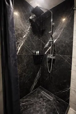a bathroom with a shower with black marble at Stay Here In Casablanca Center in Oulad Akkou