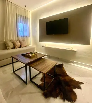 a living room with a table and a tv on a wall at Stay Here In Casablanca Center in Oulad Akkou