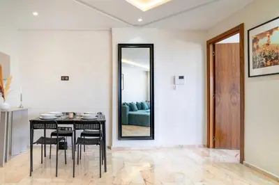 a dining room with a table and chairs and a mirror at Appartement luxueux &chaleureux Agdal rabat in Rabat