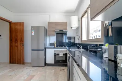 a kitchen with stainless steel appliances and a large window at Appartement luxueux &chaleureux Agdal rabat in Rabat