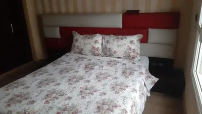 a bed with a red and white comforter and pillows at Appartement meublé à Casablanca in Casablanca