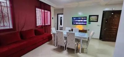 a living room with a red couch and a table and chairs at Private Room in Shared Apartment step by mosquée Hassan II in Casablanca