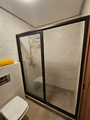 a glass shower in a bathroom with a toilet at Appartement De Standing - Face à La Plage -piscine in Mohammedia