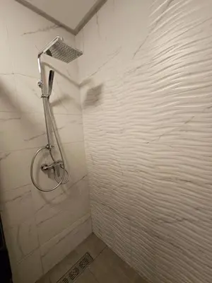 a shower in a bathroom with a white wall at Appartement De Standing - Face à La Plage -piscine in Mohammedia