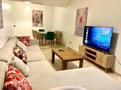 a living room with a couch and a flat screen tv at Apartment near the soccer fields in Rabat