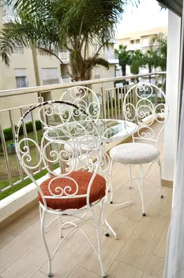 two white chairs and a glass table on a balcony at appartement with piscine & jardins - Détente à Bouznika, Rabat in Bouznika