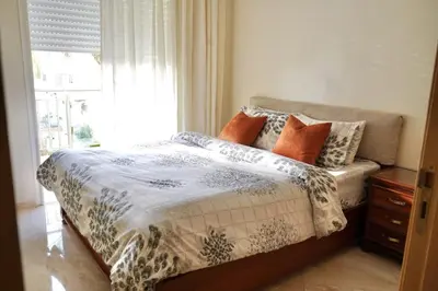 a bedroom with a bed with pillows and a window at appartement with piscine & jardins - Détente à Bouznika, Rabat in Bouznika