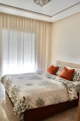 a bedroom with a bed and a window at appartement with piscine & jardins - Détente à Bouznika, Rabat in Bouznika