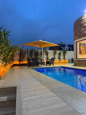 a swimming pool with a table and an umbrella at Villa 1 prestige with Pool & Private Guests Suites in Sidi Yahia az Zaʼer
