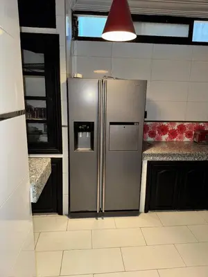a stainless steel refrigerator in a kitchen with black cabinets at Ideal appartement CAN2025 Grand Stade Rabat in Temara