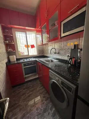 a kitchen with red cabinets and a washing machine at Apartment dar bouazza in Dar Bouazza
